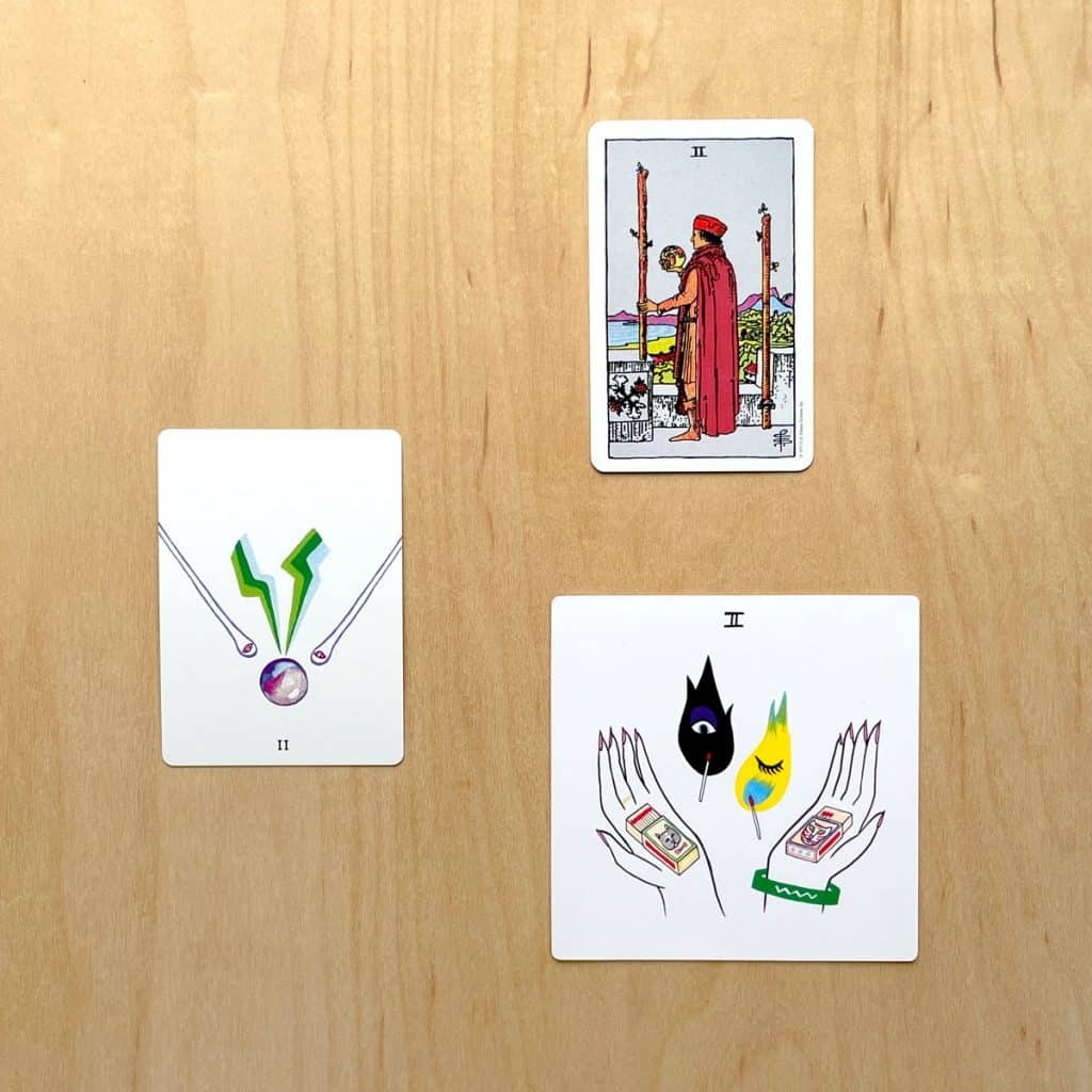 A picture of three tarot cards: The rider waite tarot, laughing eye weeping eye tarot, and colorful tears tarot